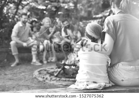 Black and white photo of mother sitting with arm around daughter while camping at par