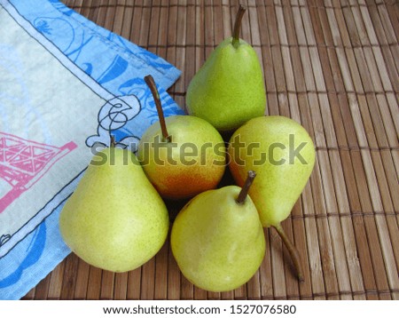 Group of ripe green pears on a wooden background with a table-napkin nearby. Autumn harvest of fruits.