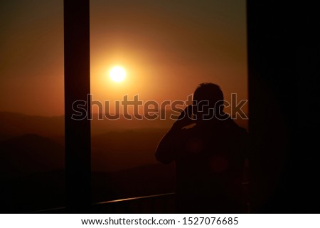 A man takes a picture of the sunset at the top of the port of Peña Negra (Peñanegra) located in the Sierra de Villafranca. Avila. Castilla and León. Spain