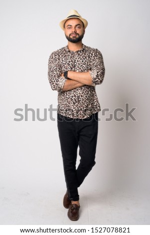 Full body shot of young bearded Indian man with arms crossed