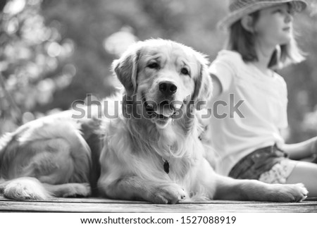 Black and white photo of Young girl fishing while sitting with dog on pier