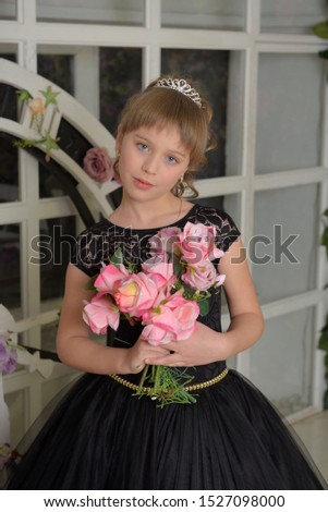 cute girl princess in a black dress with a becket of flowers in her hands