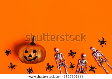 Halloween decoration concept - orange background with spiders, bats, skeletons. Flat lay, top view. Place for your text.