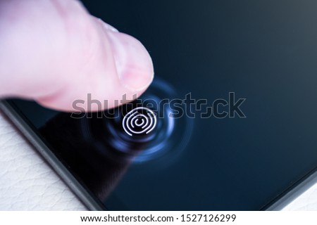 Unlocking the phone with the finger on a digital fingerprint scanner built in under the screen close up Royalty-Free Stock Photo #1527126299