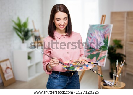 art, creativity and inspiration concept - portrait of young beautiful woman artist painting at home or studio