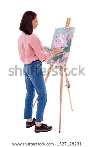 full length back view of young woman artist with easel, palette and paint brush painting picture isolated on white background
