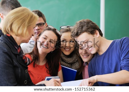 A group of happy students reading with their teacher in a classroom