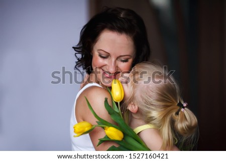 Happy mother's day. daughter congratulates mom kisses on the cheek and gives a bouquet of yellow tulips. Happy and smiling mom and daughter - Image