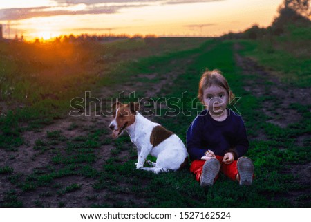 little girl and dog are resting sitting on the ground in the park