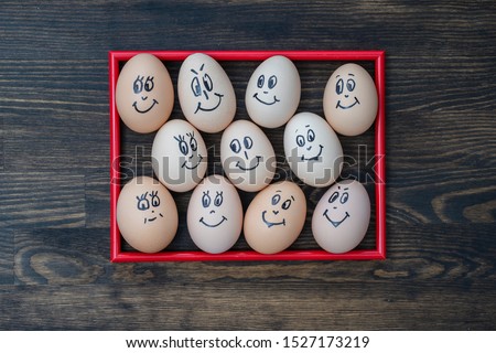 Picture red frame and many funny eggs smiling on dark wooden wall background, close up. Eggs family emotion face portrait. Concept funny food
