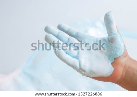 Child hand in light blue paint