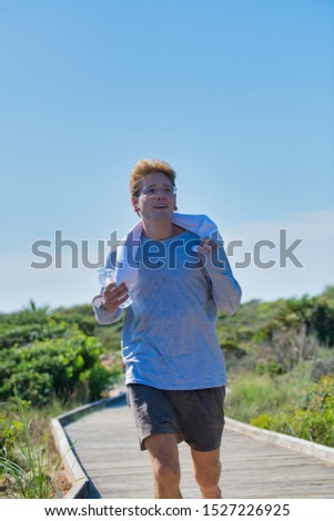 Photo portrait of a young man running in the morning with the blue sky in the background. Concept of healthy life with exercises.
