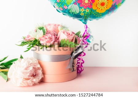 Beautiful and tender bouquet of flowers in the hat box with balloon nearby, nice present concept