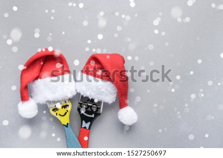 Funny christmas couple brushes with santa hats over grey