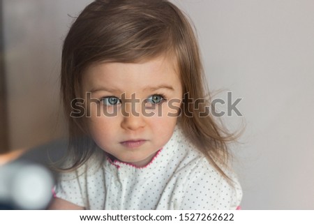 Beautiful blue-eyed preschooler or baby child girl portrait waiting or looking attentively and sadly