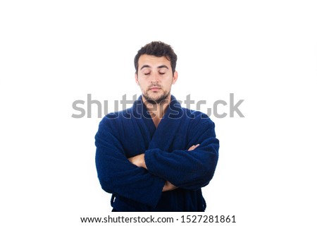 Portrait of sleepy young man wears blue bathrobe with crossed arms eyes closed feel tired needs to sleep isolated on white background.