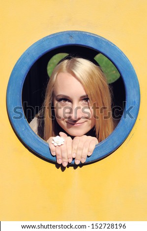 The young girl looks through a window on a playground