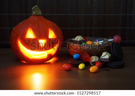                            Glowing halloween pumpkin with pile of treats in the dark    