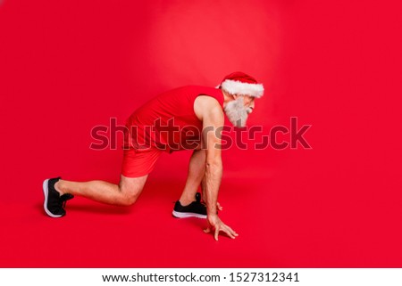 Ready steady go! Full length profile side photo of focused santa claus ready to run race wearing sports wear cap   isolated over red background