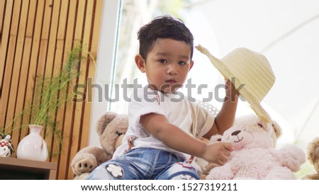 Cute Asian boy holding teddy bear on hands.                  