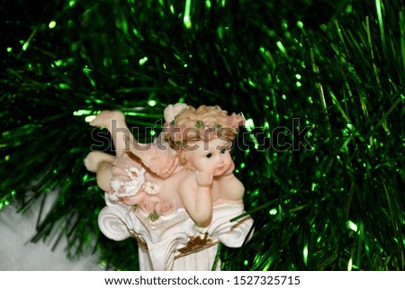 
Christmas angel with wings, lies on a column, decorated Christmas tree.