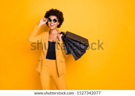 Portrait of positive cheerful afro american girl have fun on free time hold black bags addicted shopper want shop all bargains wear style outfit pants trousers isolated over yellow color background Royalty-Free Stock Photo #1527342077