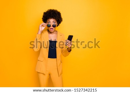 Portrait of shocked afro american girl use smartphone read news on social network account get notification about dislike scream omg wear stylish fashionable clothes isolated yellow color background Royalty-Free Stock Photo #1527342215