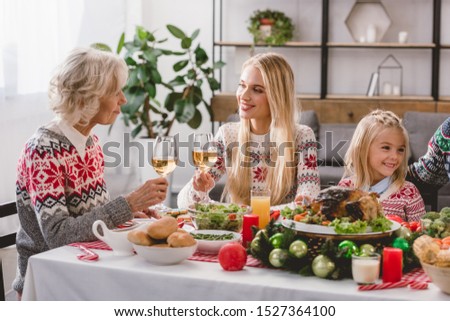 family members sitting at table and holding wine glasses in Christmas 