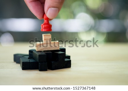 Hand put a red chess pawn on wooden puzzle against natural background for game plan and strategy concept