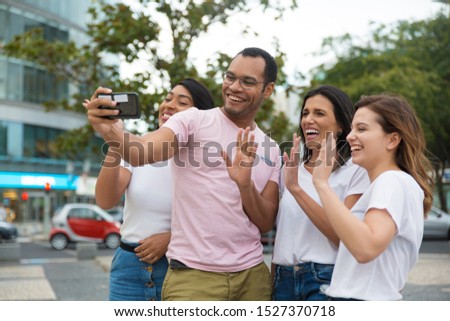 Smiling friends waving to camera phone. Group of cheerful young people posing for selfie. Concept of self portrait