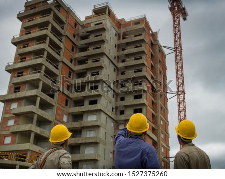 Multi-storey building under construction. Their workers with safety clothing observe the work to be done and comment on the details to be completed.