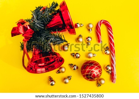christmas decor on yellow background. christmas tree balls, bell and peppermint candy cane flat lay from top view