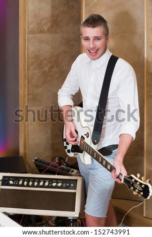 Smiling guitarist playing guitar in the studio