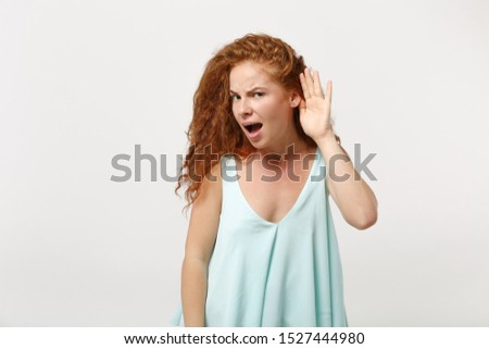 Young perplexed redhead woman girl in casual light clothes posing isolated on white wall background, studio portrait. People lifestyle concept. Mock up copy space. Try to hear you with hand near ear