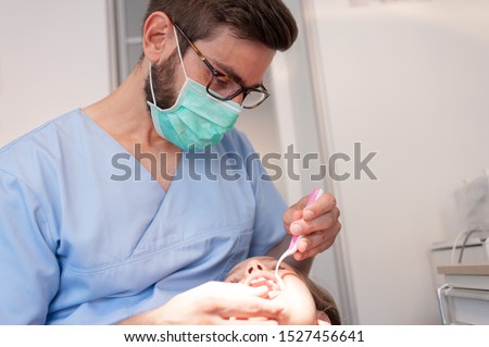 Sweet child doing a teeth examination by a professional dentist in a pediatric stomatology