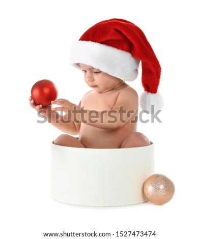 Cute little baby wearing Santa hat sitting in box with Christmas decorations on white background
