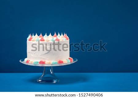 Birthday cake with pastel icing, c over a blue background.