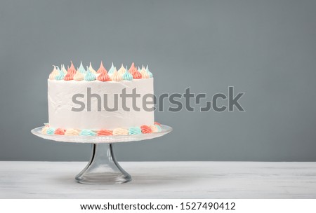 White Birthday cake with pastel icing over a grey background