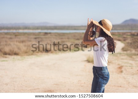 Photographer taking a picture with her old analog photography camera. Outdoor. Desert landscape
