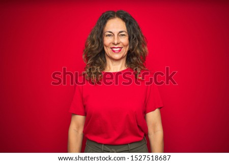Middle age senior woman with curly hair over red isolated background with a happy and cool smile on face. Lucky person.