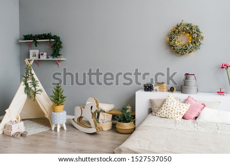 The interior of the bedroom or children's room decorated for Christmas or New Year: bed, wigwam, children's swing horse, Christmas wreath on the wall Royalty-Free Stock Photo #1527537050