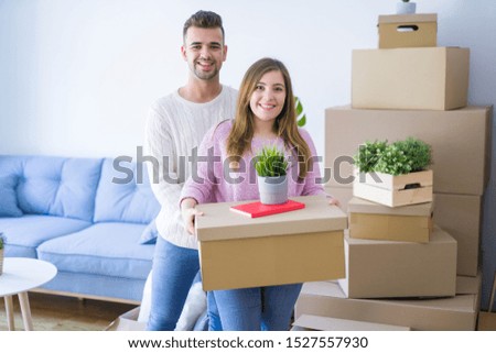 Young beautiful couple in love moving to new home, holding cardboard boxes very happy and cheerful for new apartment