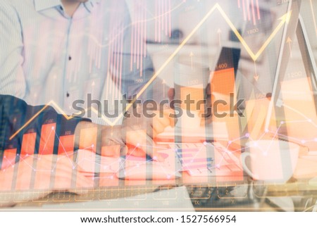Multi exposure of chart with man typing on computer in office on background. Concept of hard work.