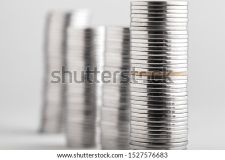 Coins stacked on top of one another with a gold coin. On a white background.