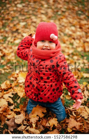Young angry child in park during autumn with colourful leaves. 