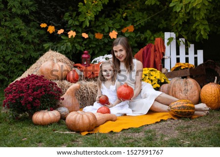 mother and daughter in autumn background with pumpkins
