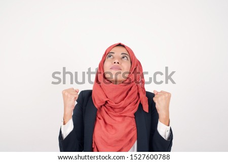 Excited Young muslim businesswoman winner raising his fists with great happiness having good mood having success being glad to achieve her goals. Victory and triumph concept.