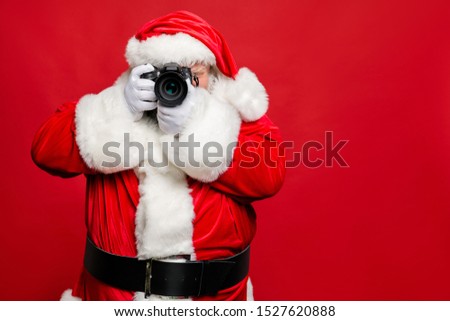 Portrait of focused elderly santa claus hipster take photo of his christmas time voyage abroad wear stylish costume belt gloves isolated over red background