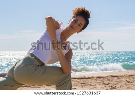 Yoga teacher doing some yoga exercises by the beach. Morning routine.