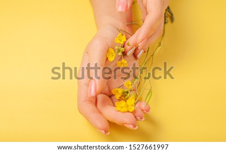 Hands art flower natural cosmetics women, yellow beautiful, spring flowers hand with bright contrast makeup, hand care. Fashion, creative beauty photo girl sitting at table,  yellow  background.